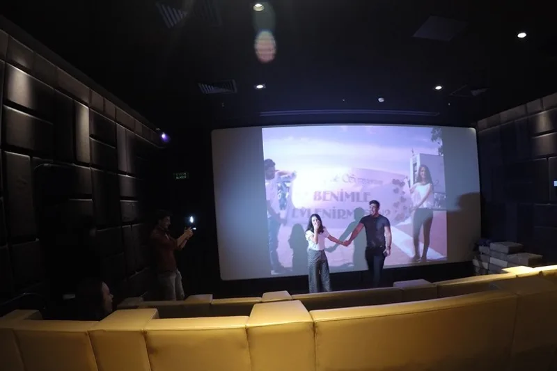 Sinema perdesinde benimle evlenir misin yazısı önünde el ele duran çift
